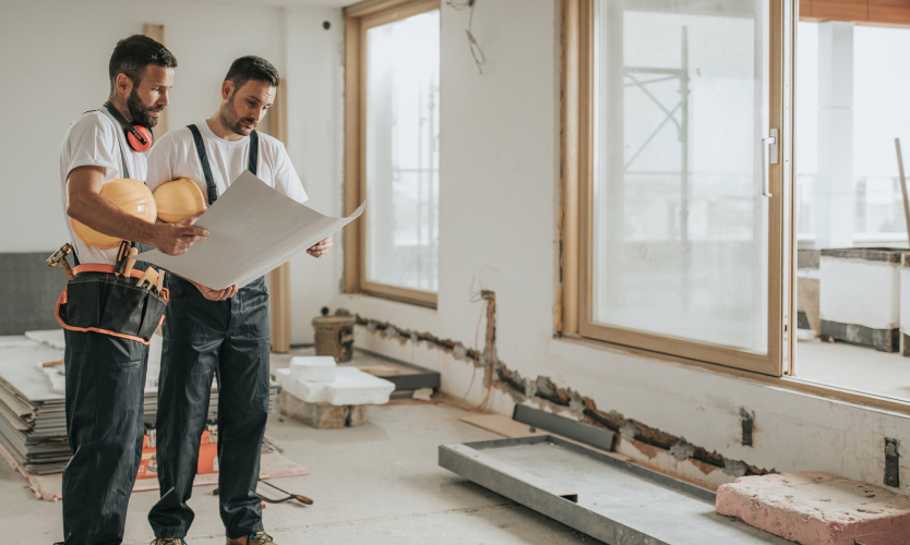 Two contractor men looking at a blueprint together