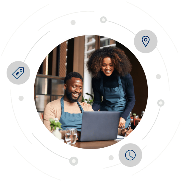 A man and a woman in an apron working together in front of a laptop