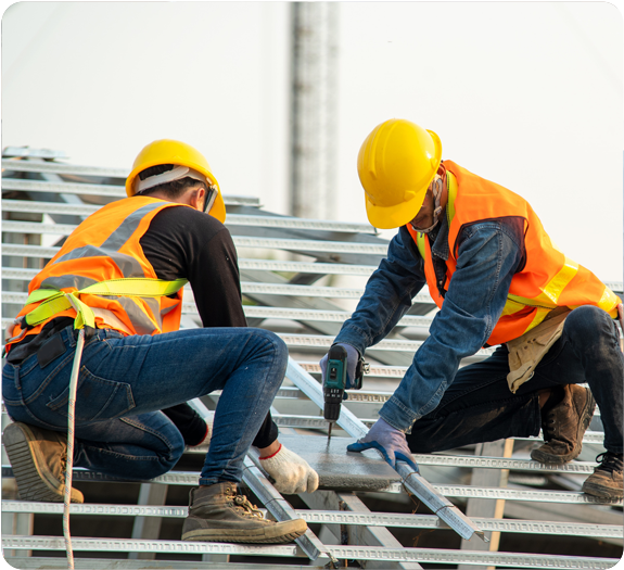 Two male roofers with yellow hard hats and orange safety vests working on a roof together 