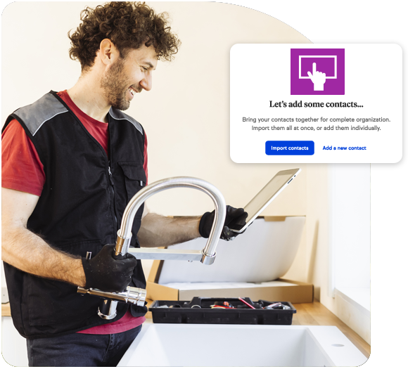 Male plumber holding a tablet and smiling as he holds a faucet he's installing