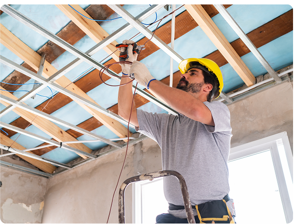 Electrician standing on a ladder installing wiring in a ceiling frame providing amazing customer satisfaction.