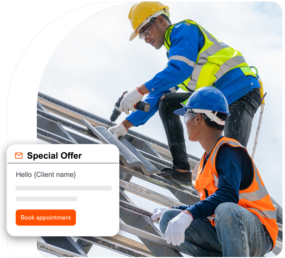 Two roofers with yellow hard hats and safety vests on nailing down a new shingle